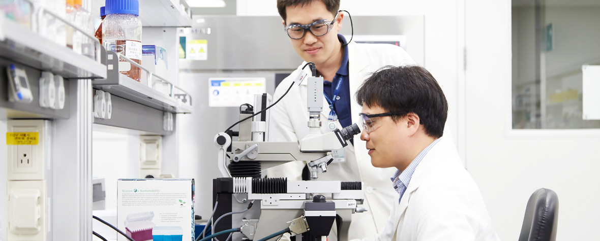 Screen image of two scientists working through a microscope